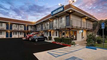A motel with a 'Welcome' sign, a parking lot, and a fire lane.
