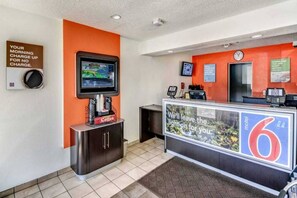 Una zona d'atenció al client amb una pantalla digital, un racó de cafè i un taulell amb un rètol.