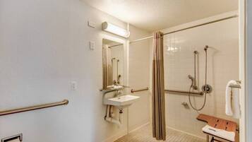 A bathroom with a walk-in shower, a sink, and a bench.