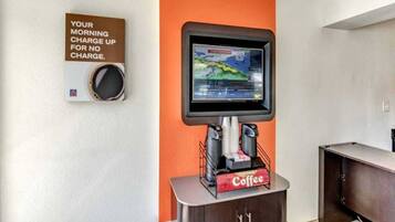 A coffee station with a coffee machine, a coffee dispenser, and a sign about morning charge.