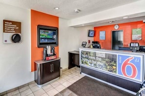 A reception area with a digital screen, a coffee station, and a counter with a sign. - 2 Full Beds | Non-Smoking (Stockton)