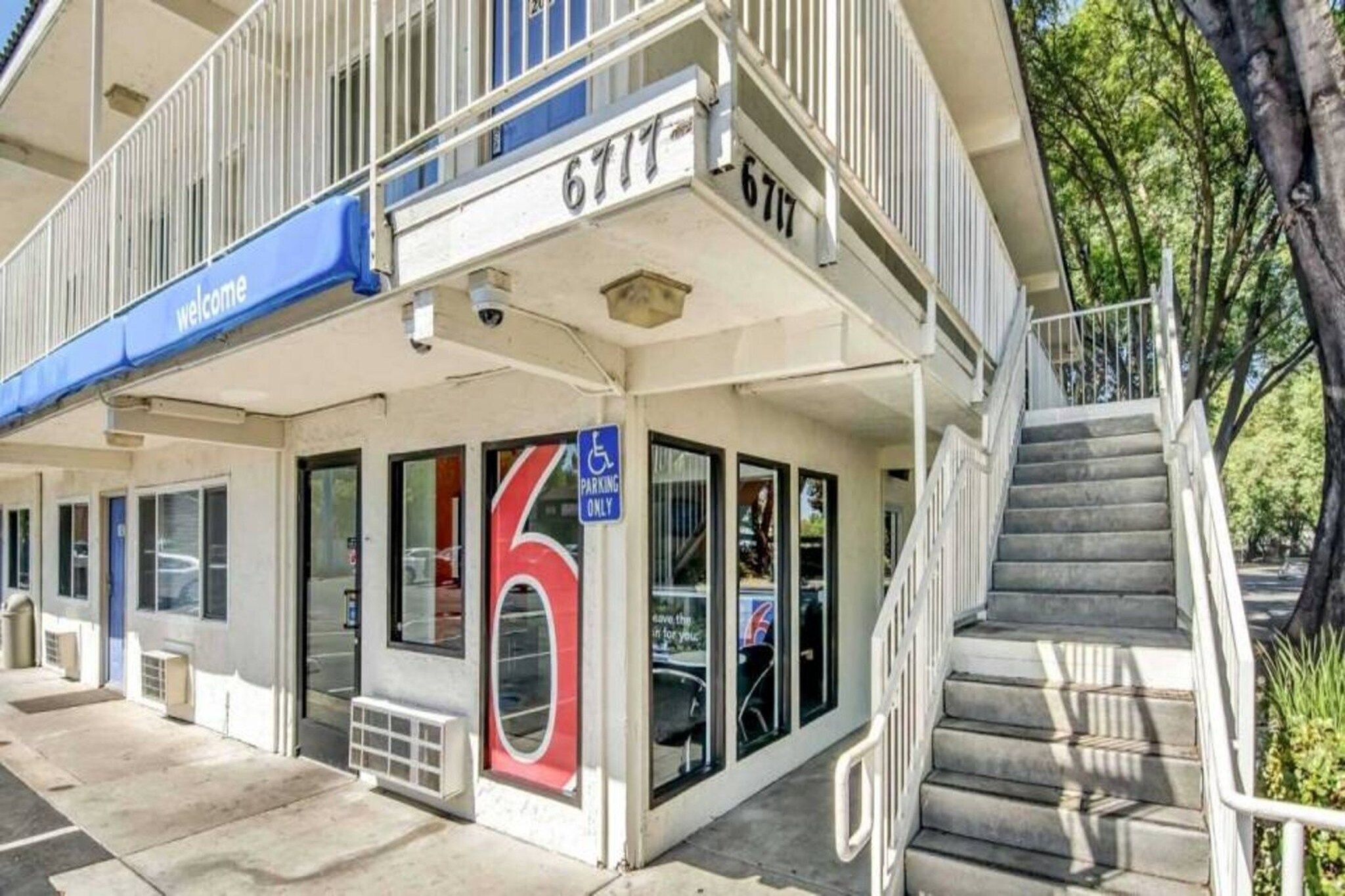 A building with a 'Welcome' sign, a large number '6' sign, and a parking sign indicating 'PARKING ONLY'.