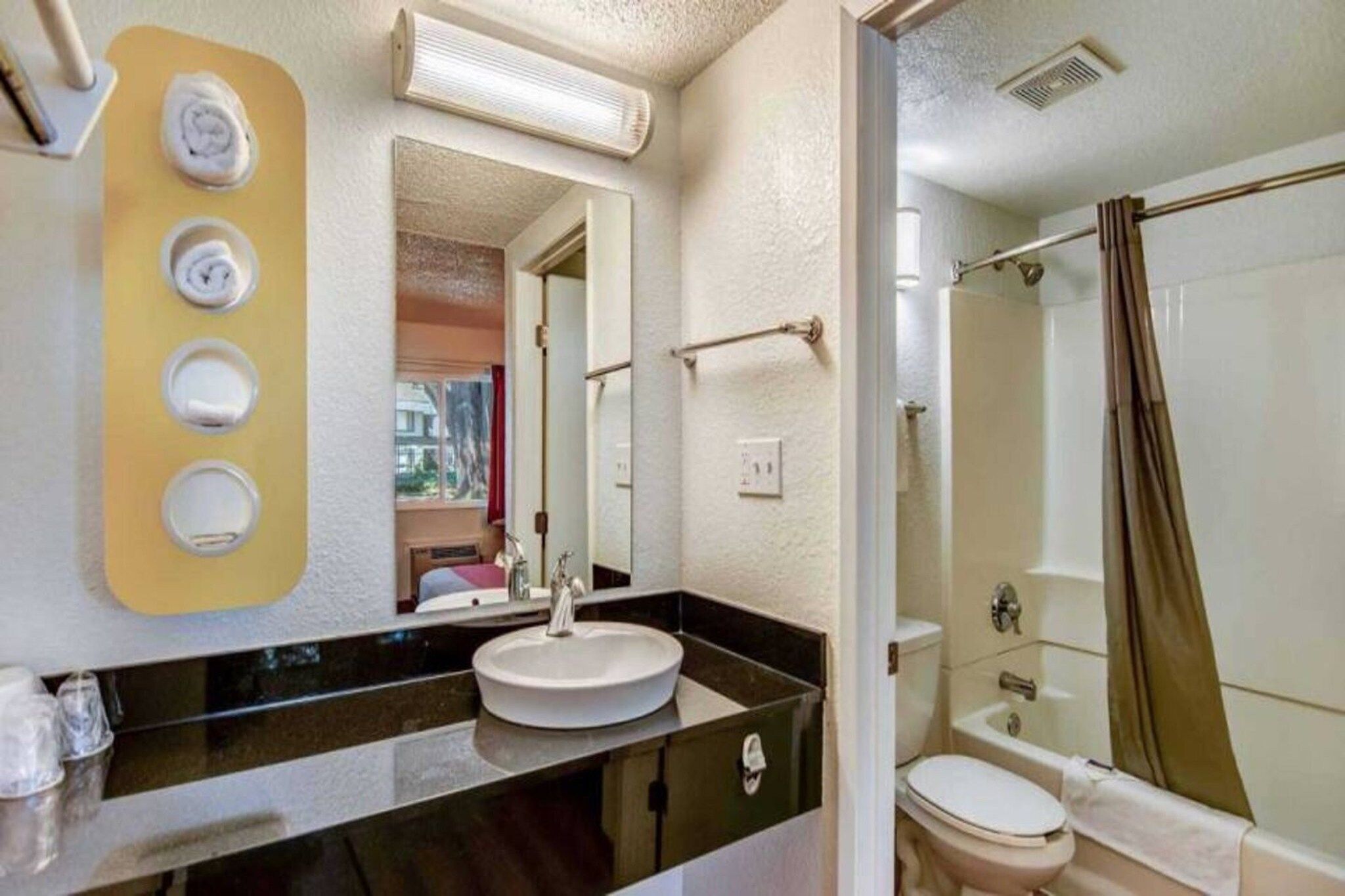 A bathroom with a sink, mirror, and shower.