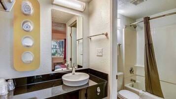 A bathroom with a sink, mirror, and shower.