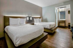 Habitación de hotel con dos camas, piso de madera y vistas al exterior.
