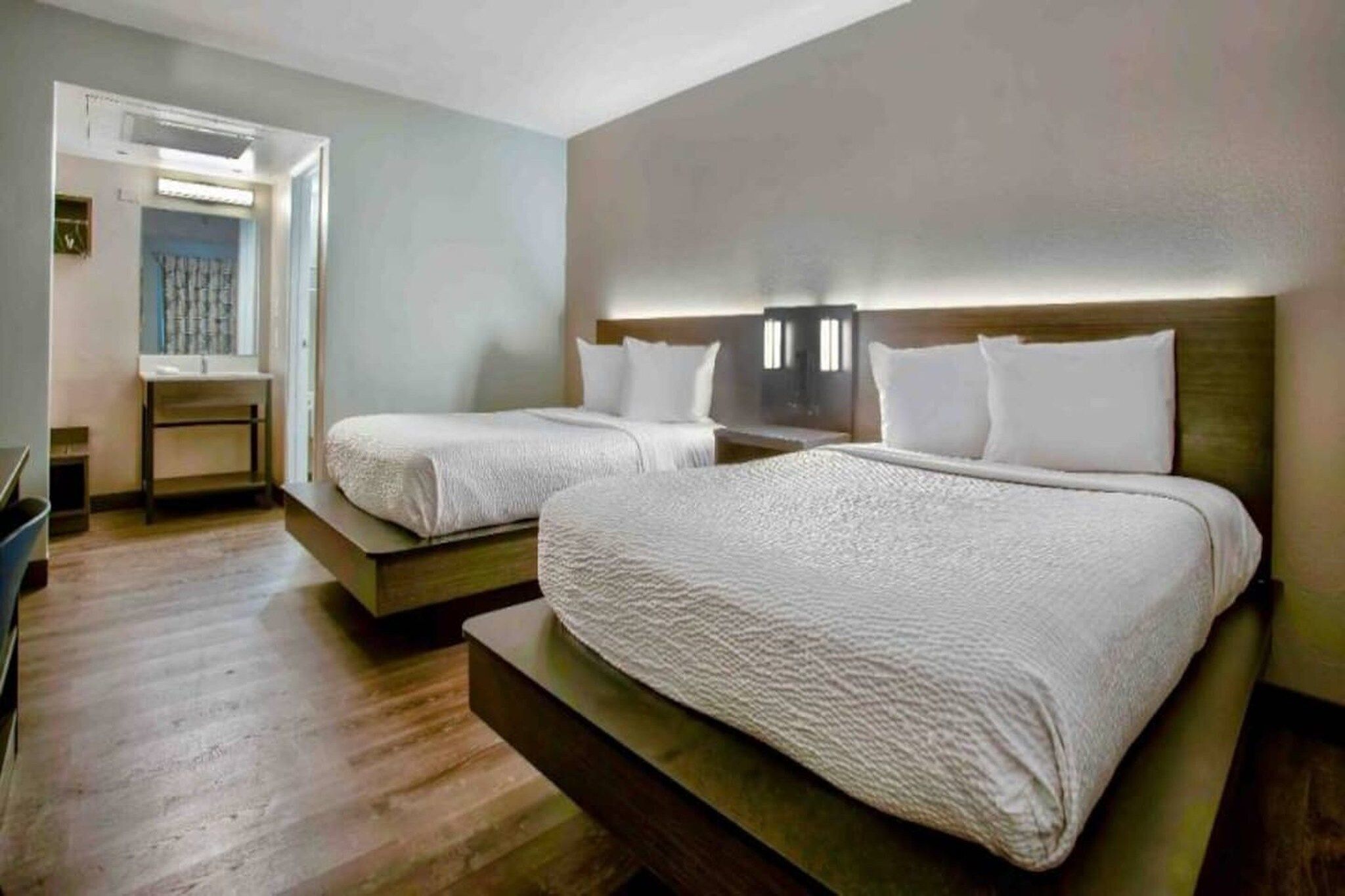 Una habitación de hotel con dos camas, un escritorio y una silla.