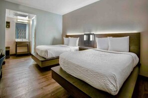 A hotel room with two beds, a desk, and a chair.