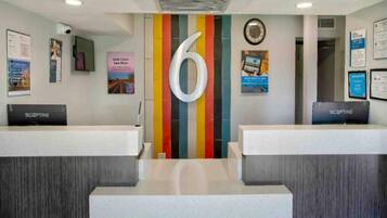 A reception area with two counters, a large number '6' on the wall, and various informational posters.