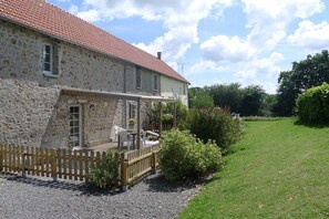 A stone house with a red-tiled roof, a wooden deck, and a gravel driveway. - Holiday home in Vesly with swimming pool (Vesly)