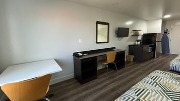 A compact living space with a desk, chair, and a bed with patterned bedding.