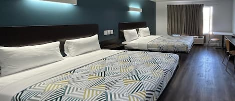 A hotel room with two beds, a desk, and a chair.