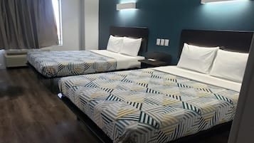Hotellihuone, jossa on kaksi sänkyä, ikkuna verhoilla, seinälle asennettu ilmastointilaite ja yöpöytä.