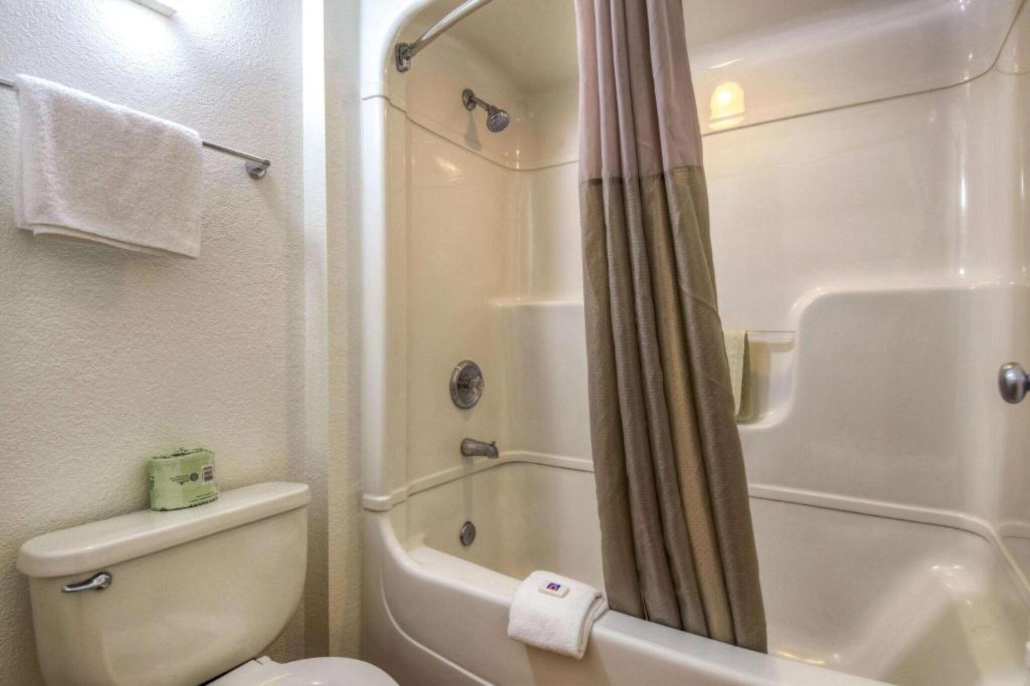A bathroom with a toilet, a shower with a curtain, and a towel rack.