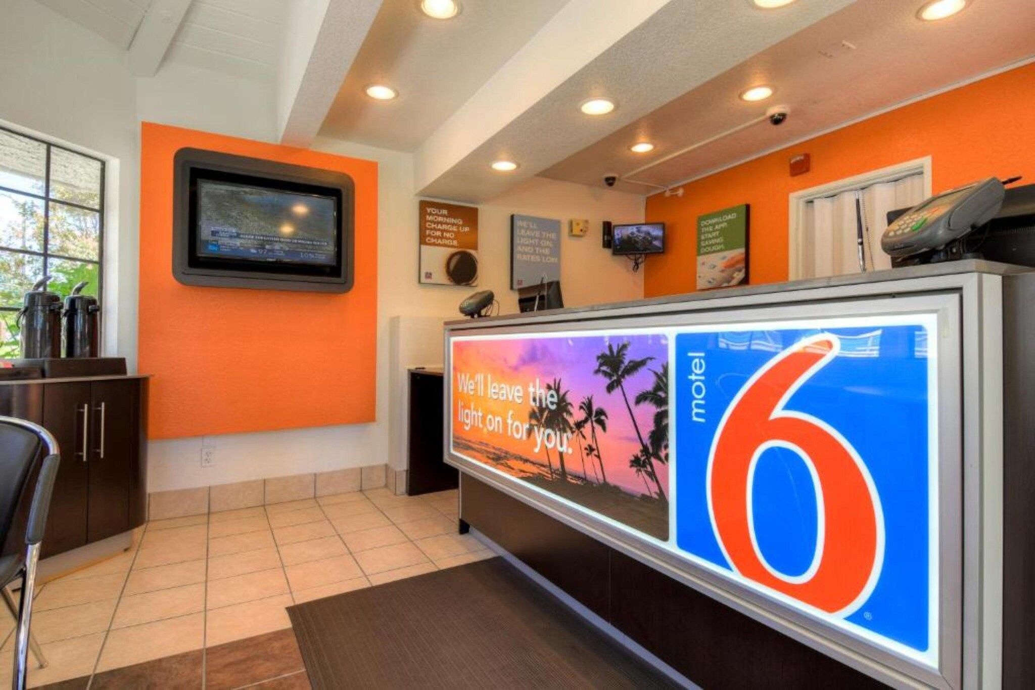 A hotel reception area with a large digital display advertising a motel.