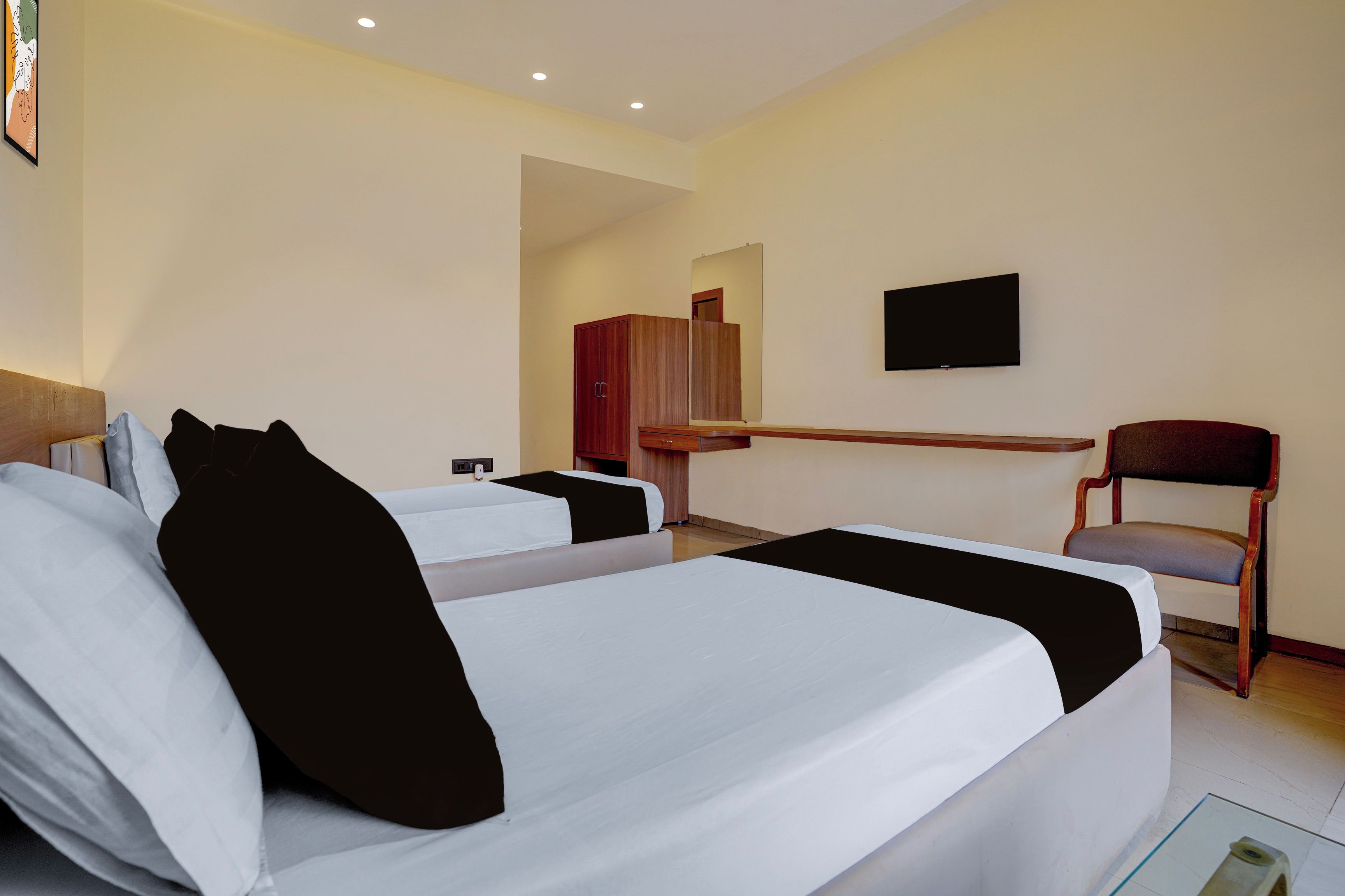 Una habitación de hotel con dos camas, un escritorio, una silla, un televisor y un armario.