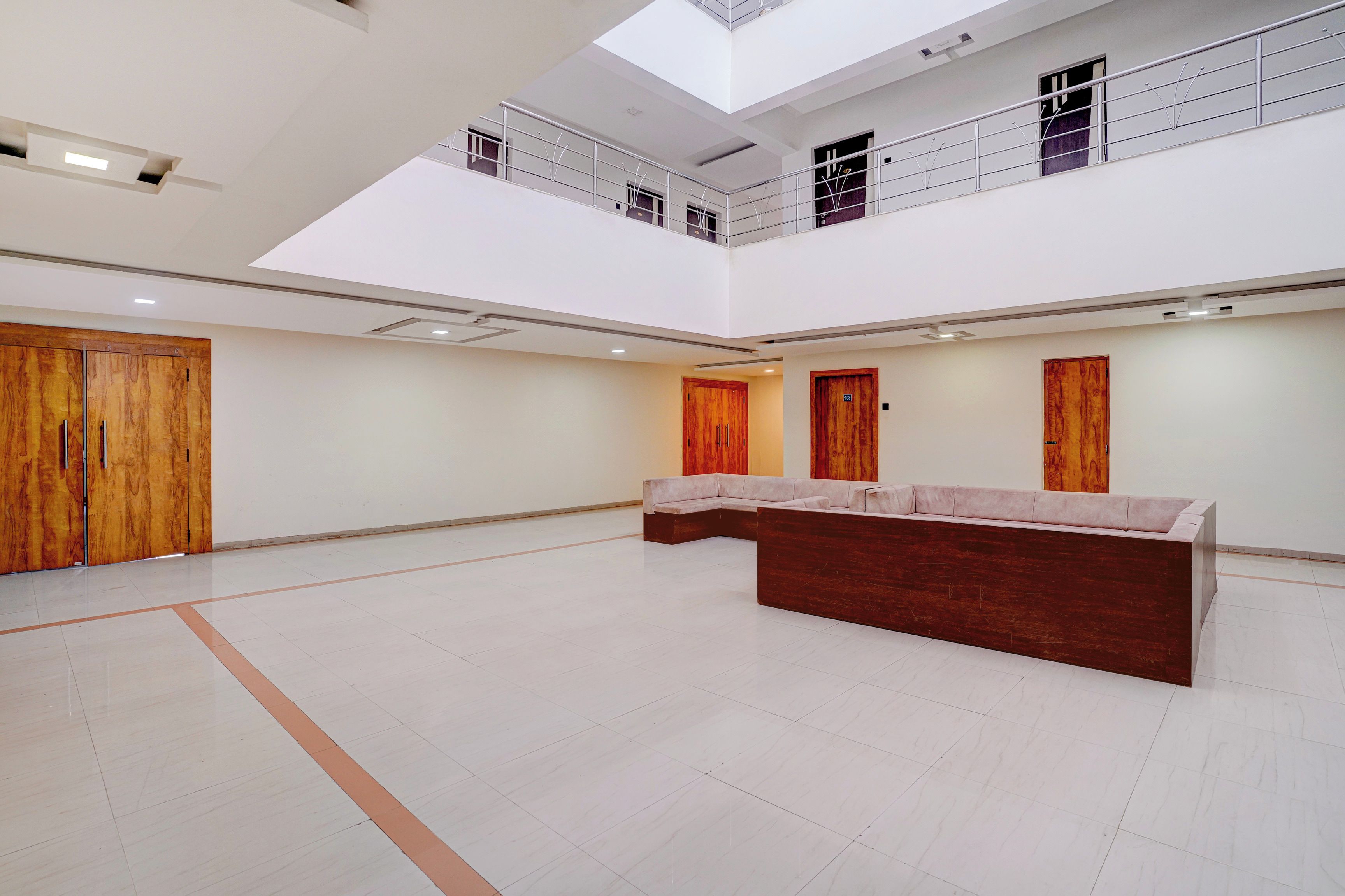 Un interior espacioso y de varios niveles, con una zona de estar central, puertas de madera y un balcón.