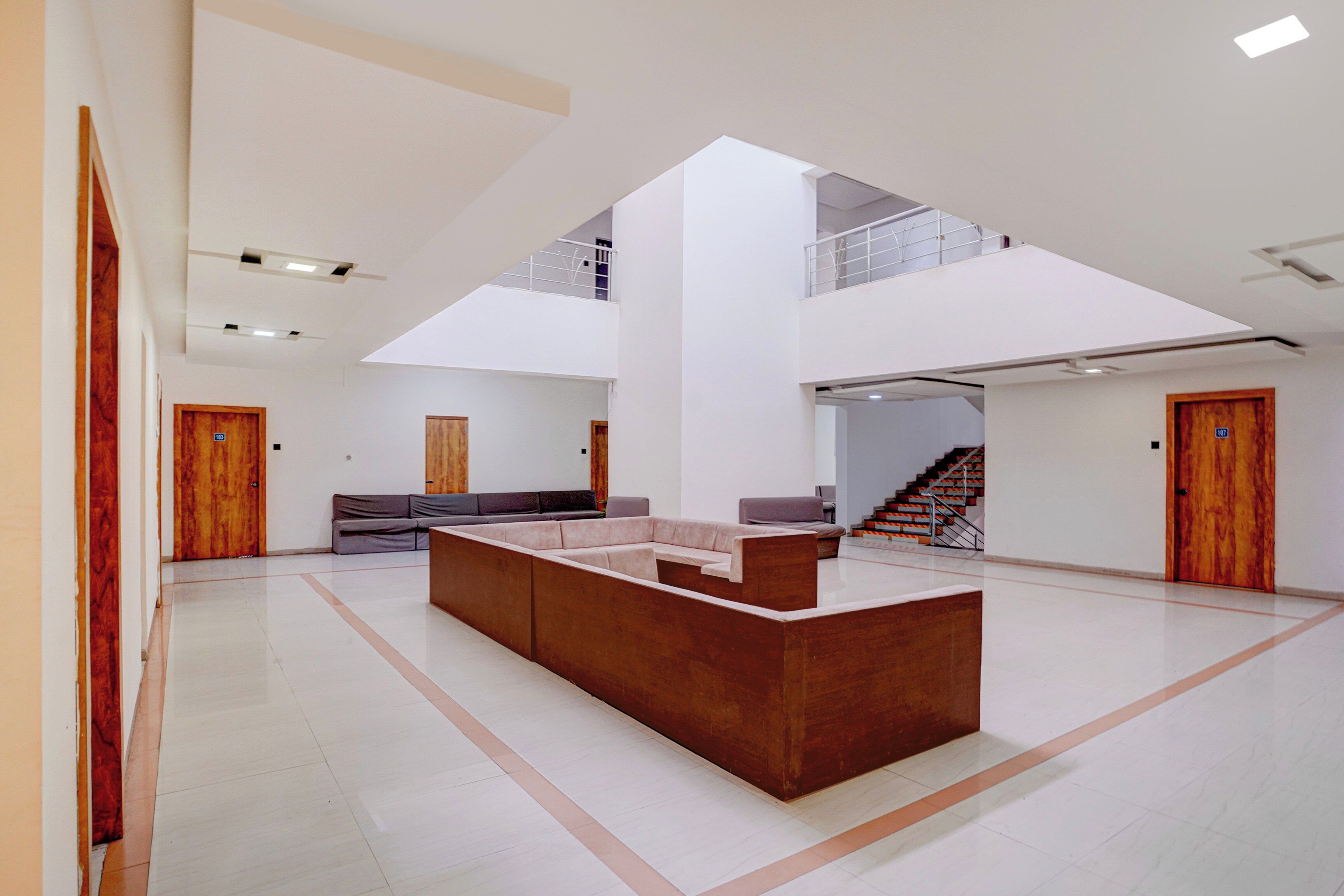 A spacious interior with a central seating area, a staircase, and a high ceiling.