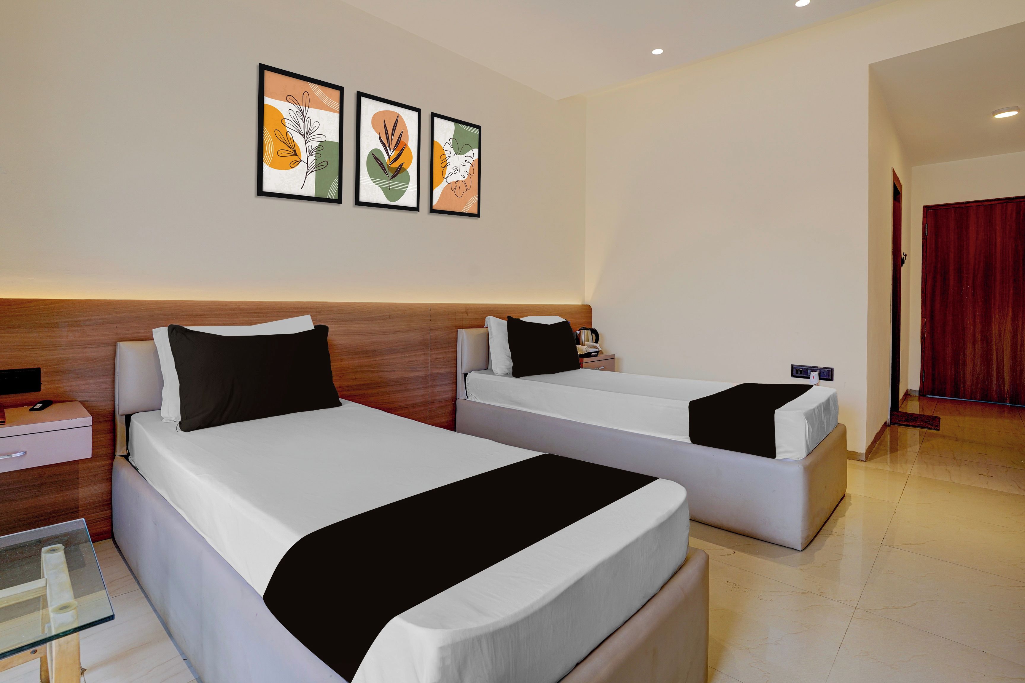 Habitación de hotel con dos camas, una mesita de noche y un televisor montado en la pared.