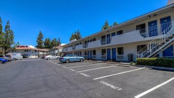 A motel with a parking lot, compact parking spaces, and a building with multiple rooms.