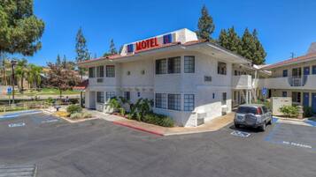 A two-story motel with a sign indicating it is number 6. There are parking spaces with a no parking sign visible.