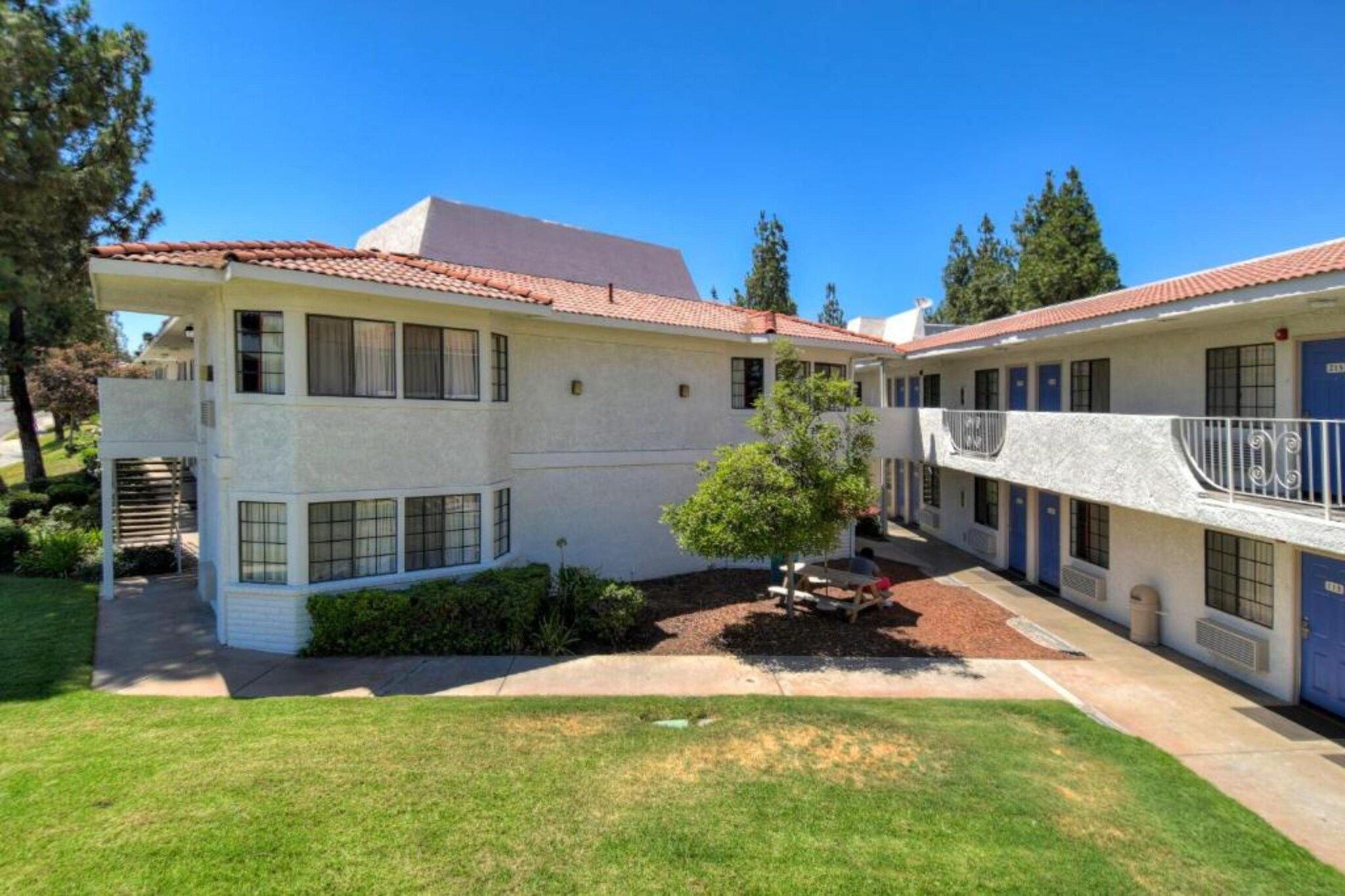 A two-story building with a flat roof and a small garden area.