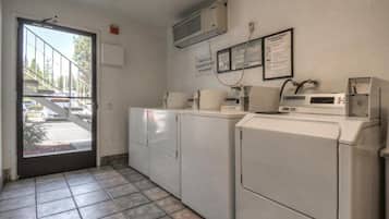 Une buanderie avec une porte donnant sur l’extérieur, un lave-linge, un sèche-linge et un climatiseur fixé au mur.