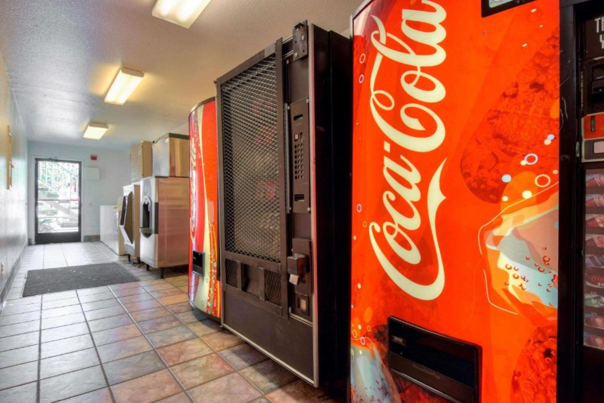 A hallway with vending machines, a refrigerator, and a microwave.