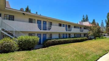A two-story motel with a central courtyard, a covered outdoor seating area, and a parking lot.