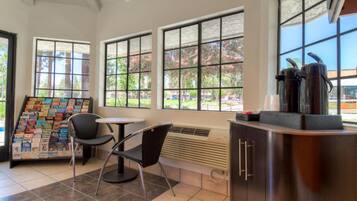 A modern interior with a book display, a table, chairs, and a coffee station.