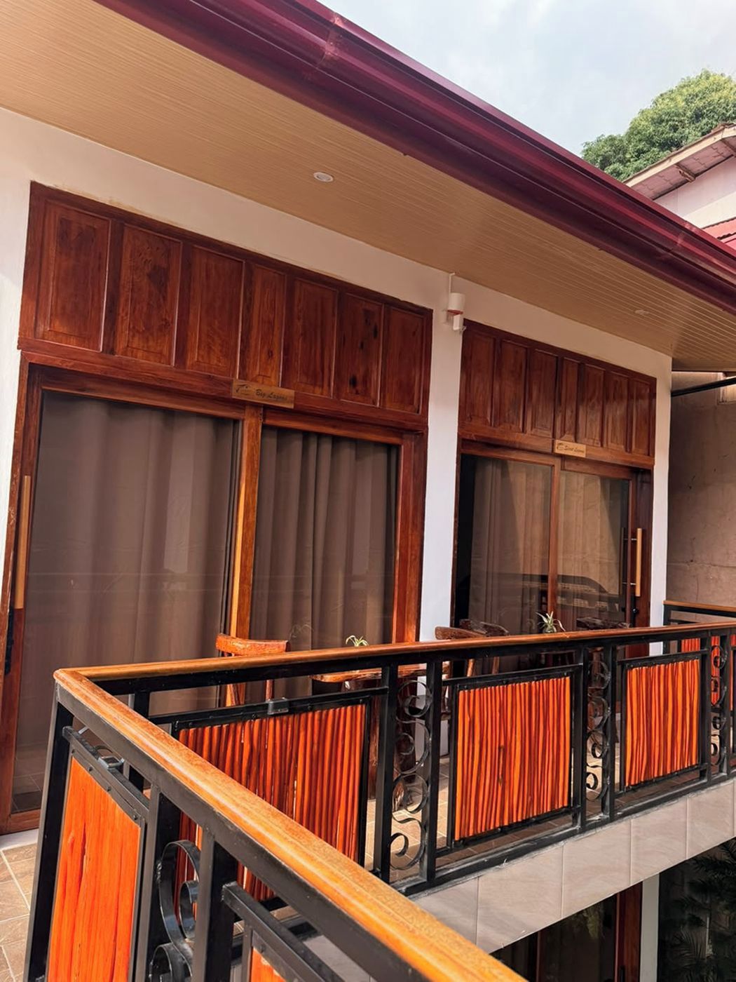 A balcony with wooden railings and a view of a building with large windows and wooden paneling.