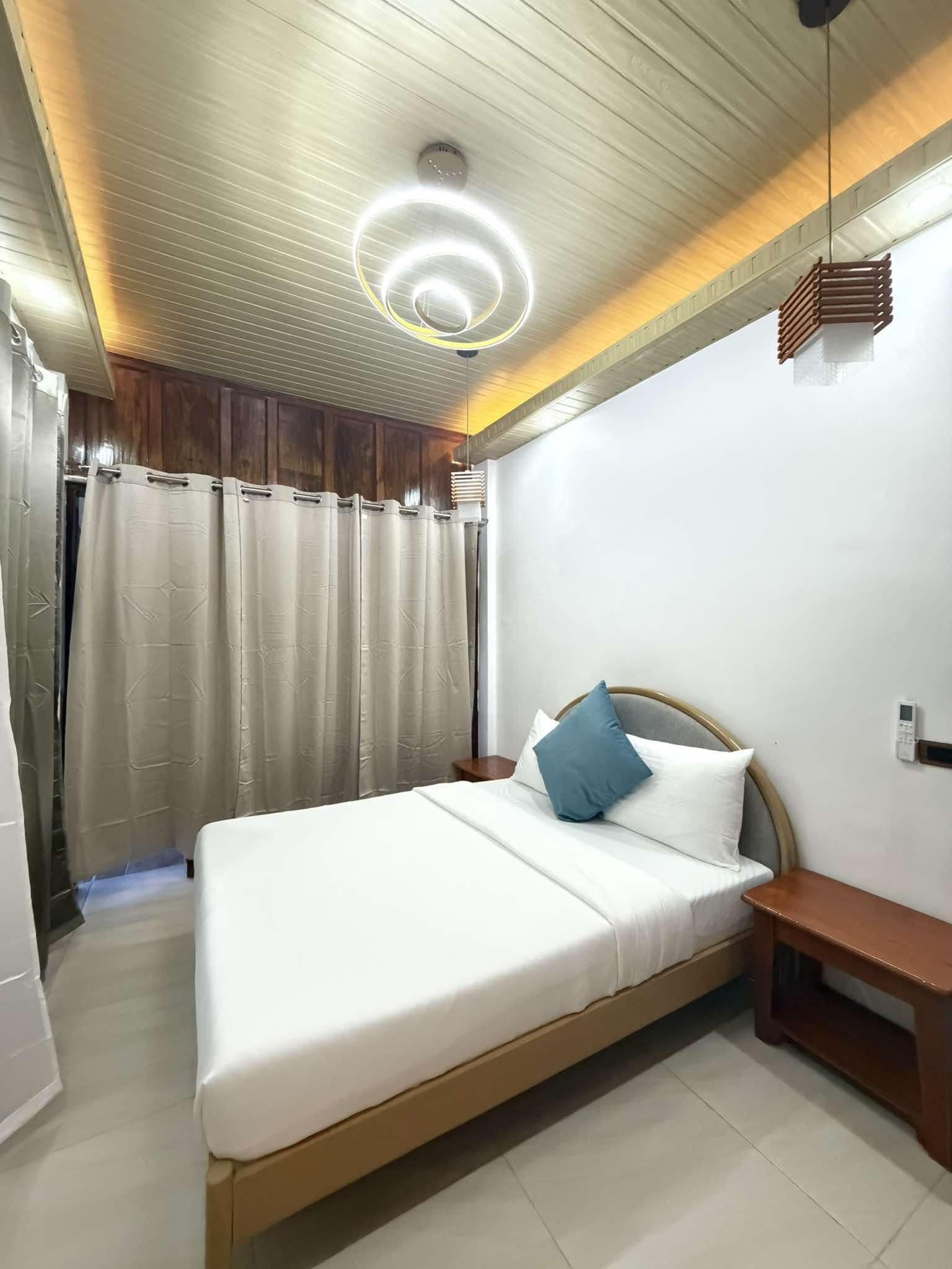 Une chambre à coucher comprenant un lit, une table de chevet, un téléphone fixé au mur et un luminaire au plafond.