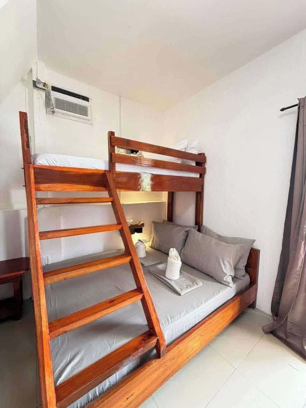 A bunk bed with a wooden ladder, a bedside table, and a small lamp.
