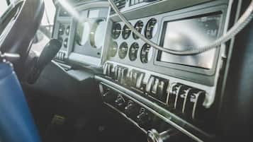 A vintage car dashboard with a steering wheel, multiple gauges, and a radio.