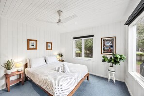 Ein Schlafzimmer mit Bett, Fenster, Deckenventilator und einem Poster an der Wand.