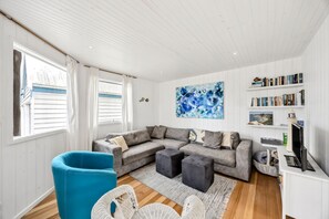 A modern living room with a sectional sofa, a blue armchair, and a large abstract painting. - Aireys Sea & River Retreat family friendly escape (Aireys Inlet)