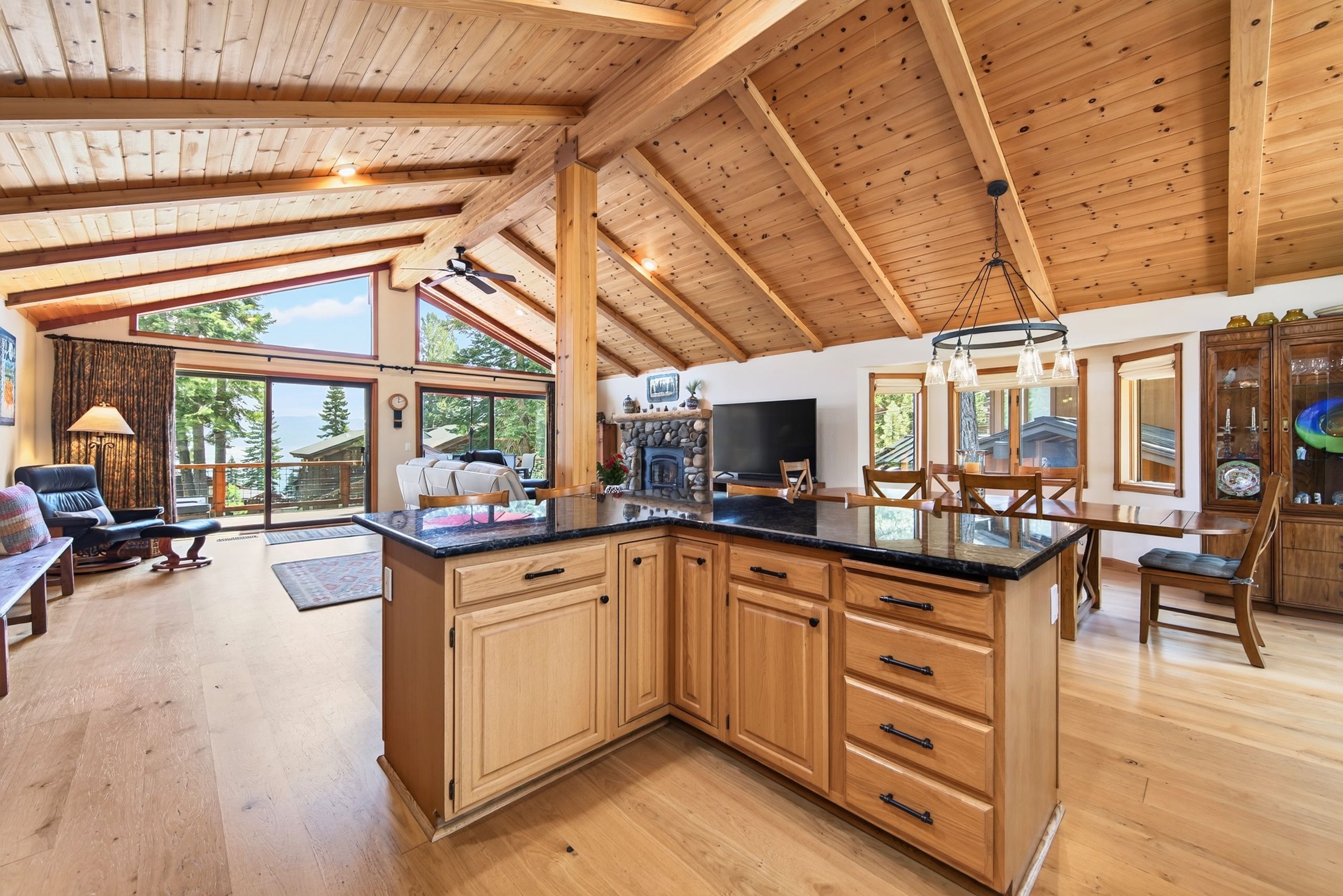 A spacious kitchen with wooden cabinets, a large island, and a dining area with a view of the outdoors.