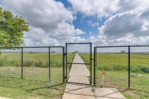 Un área cercada con una reja, un camino de concreto y un campo cubierto de césped.
