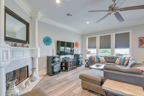 Una sala de estar moderna con chimenea, un sofá modular grande, un ventilador de techo y un televisor montado en la pared.