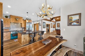 A modern kitchen with a central island, wooden cabinetry, and a chandelier. - The Cascade Ranch House | 24 Acres of Idaho Mountain Country (Cascade)