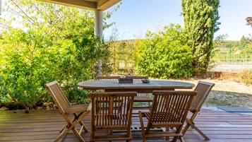 Una terraza exterior de madera con una mesa redonda y cuatro sillas.