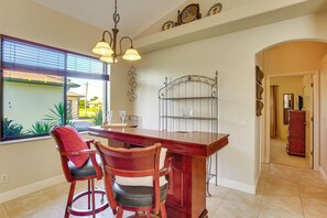 Un coin repas avec une table et des chaises en bois, un lustre et une vue par la fenêtre.