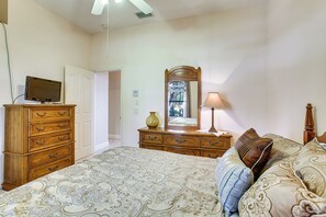 Ein Schlafzimmer mit Bett, Kommode, Spiegel, Lampe und Fernseher.