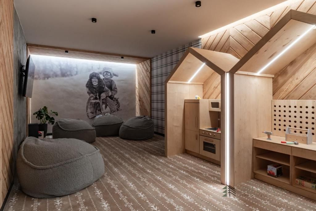 A room with a wooden sloped ceiling, a mural, bean bags, and a play area with a pegboard.