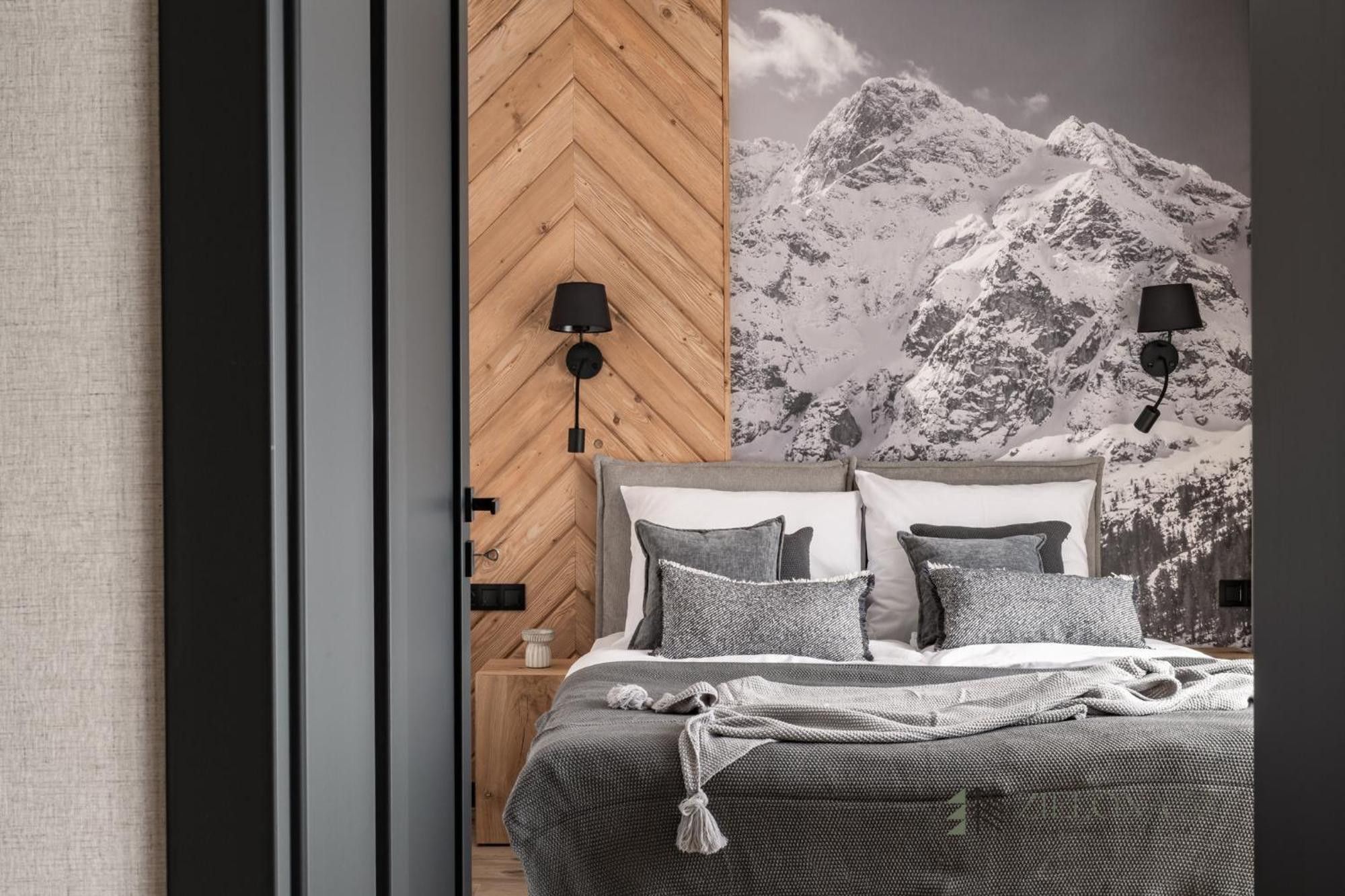 Un dormitorio con una cama, dos lámparas de noche, una mesita de noche y una pared decorada con una imagen de montaña.