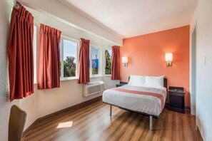 Un dormitorio con una cama, dos mesitas de noche, un radiador y cortinas en las ventanas.