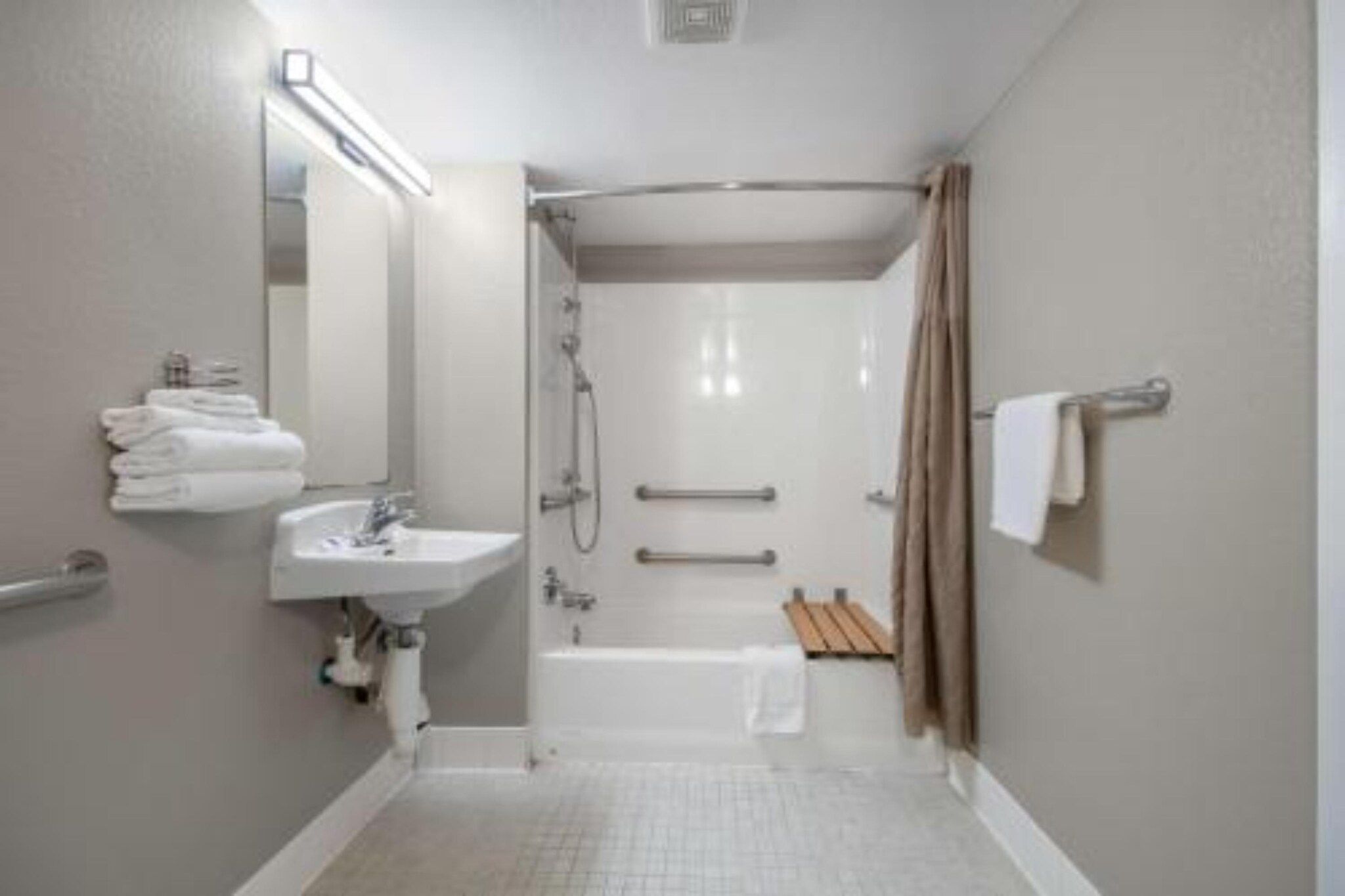 A bathroom with a sink, mirror, shower, and towel rack.