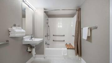 A bathroom with a sink, mirror, shower, and towel rack.