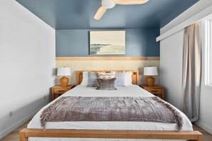 A bedroom with a bed, nightstands, a ceiling fan, a painting, and a window with curtains. - The Blue Lagoon - in Pacific Beach w/ comm pool (San Diego)