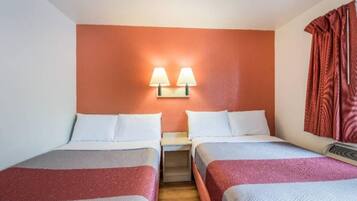 A hotel room with two beds, a nightstand, a wall-mounted lamp, and a window with curtains.