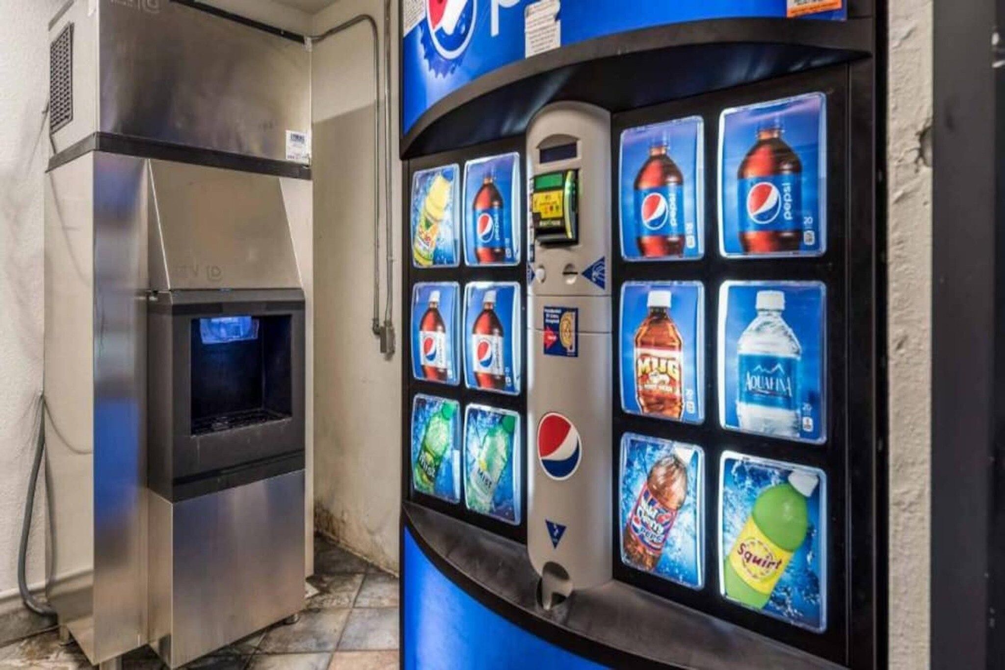 Een automaat met diverse drankjes, waaronder Pepsi, M&Ms, Aquafina water en Squirt.